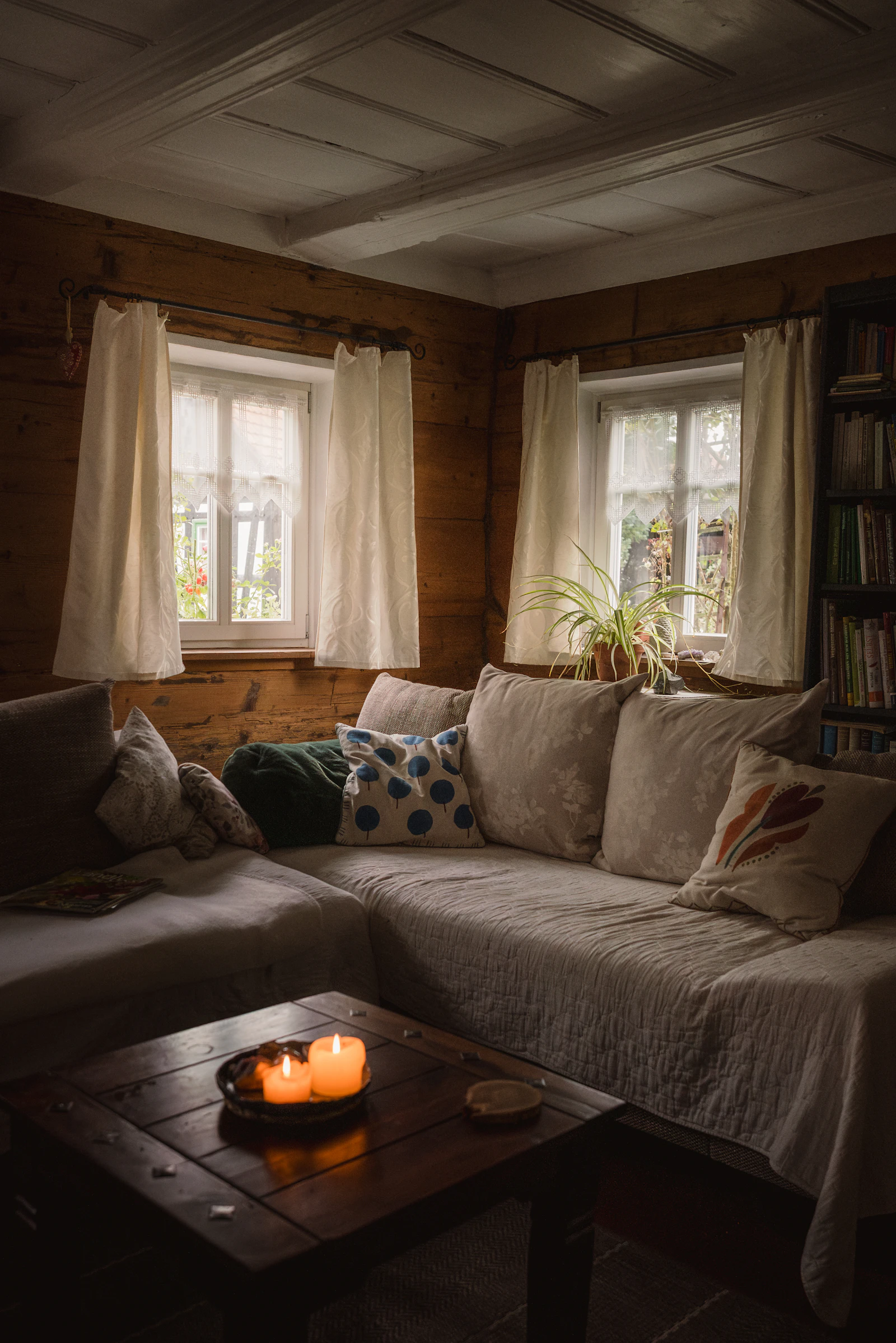 Cozy small living room with wooden walls, a sofa and lit candles